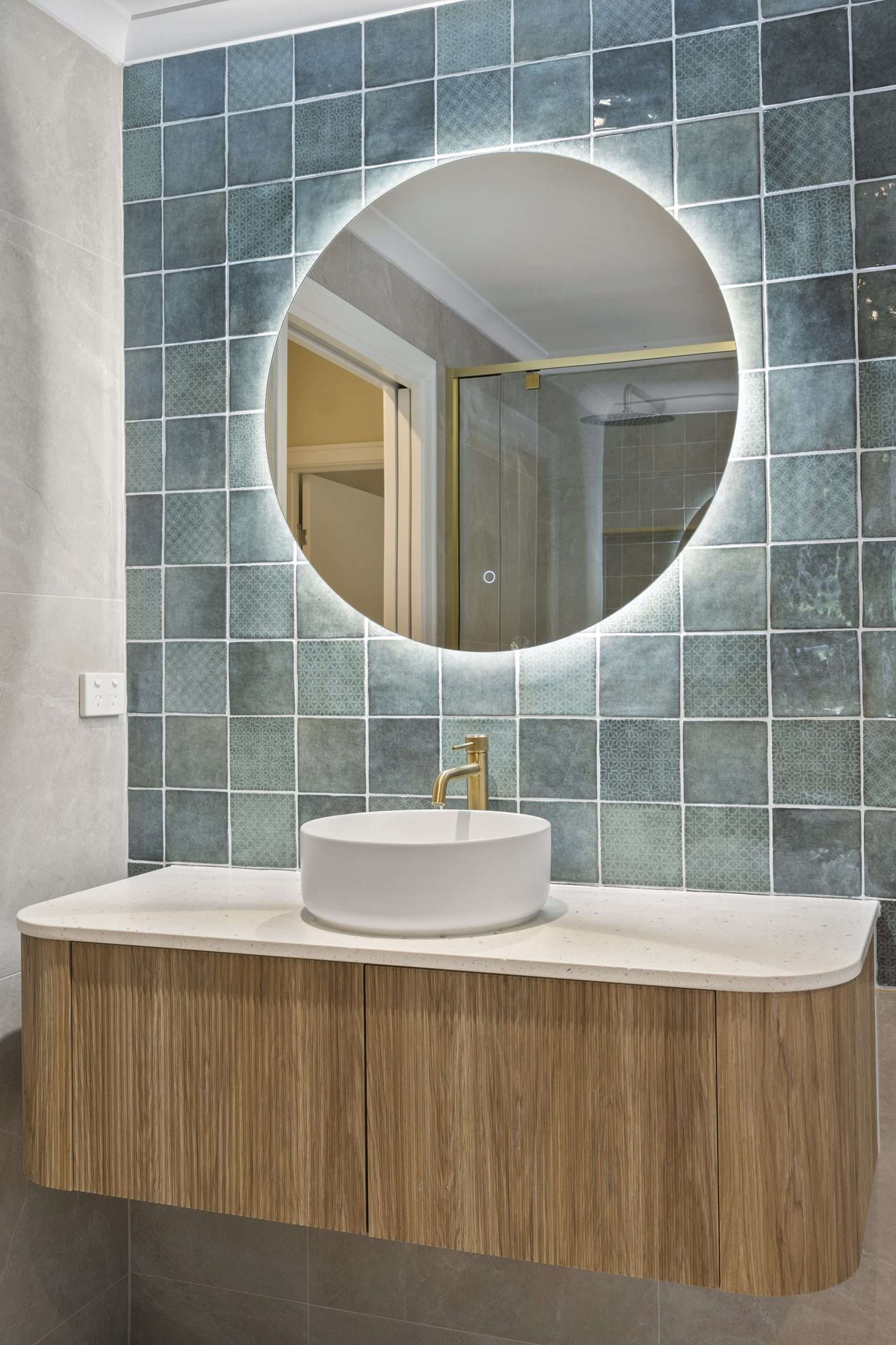 Renovated bathroom with round backlit mirror and timber vanity