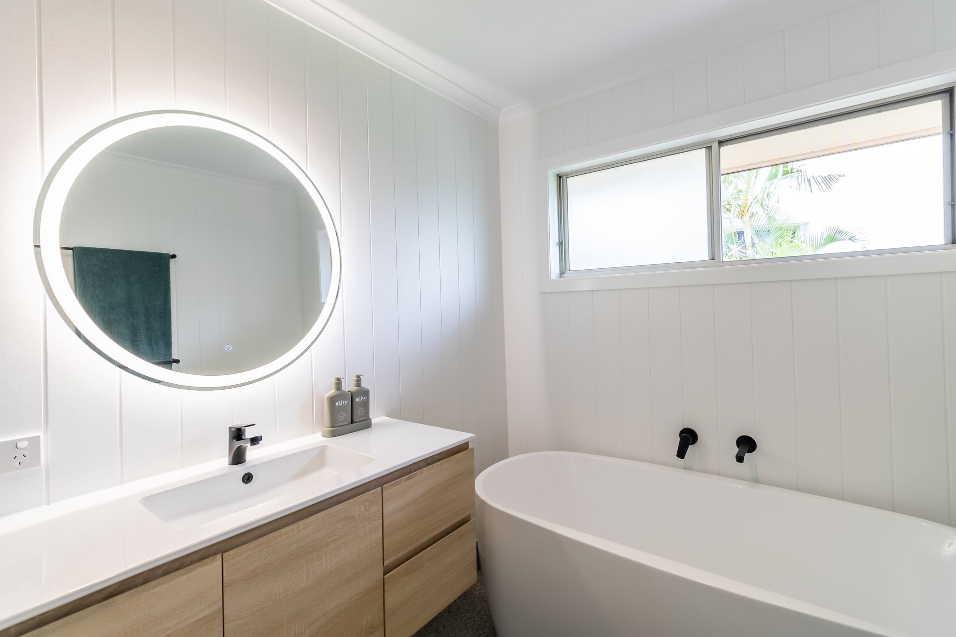Modern bathroom with illuminated round mirror and floating vanity